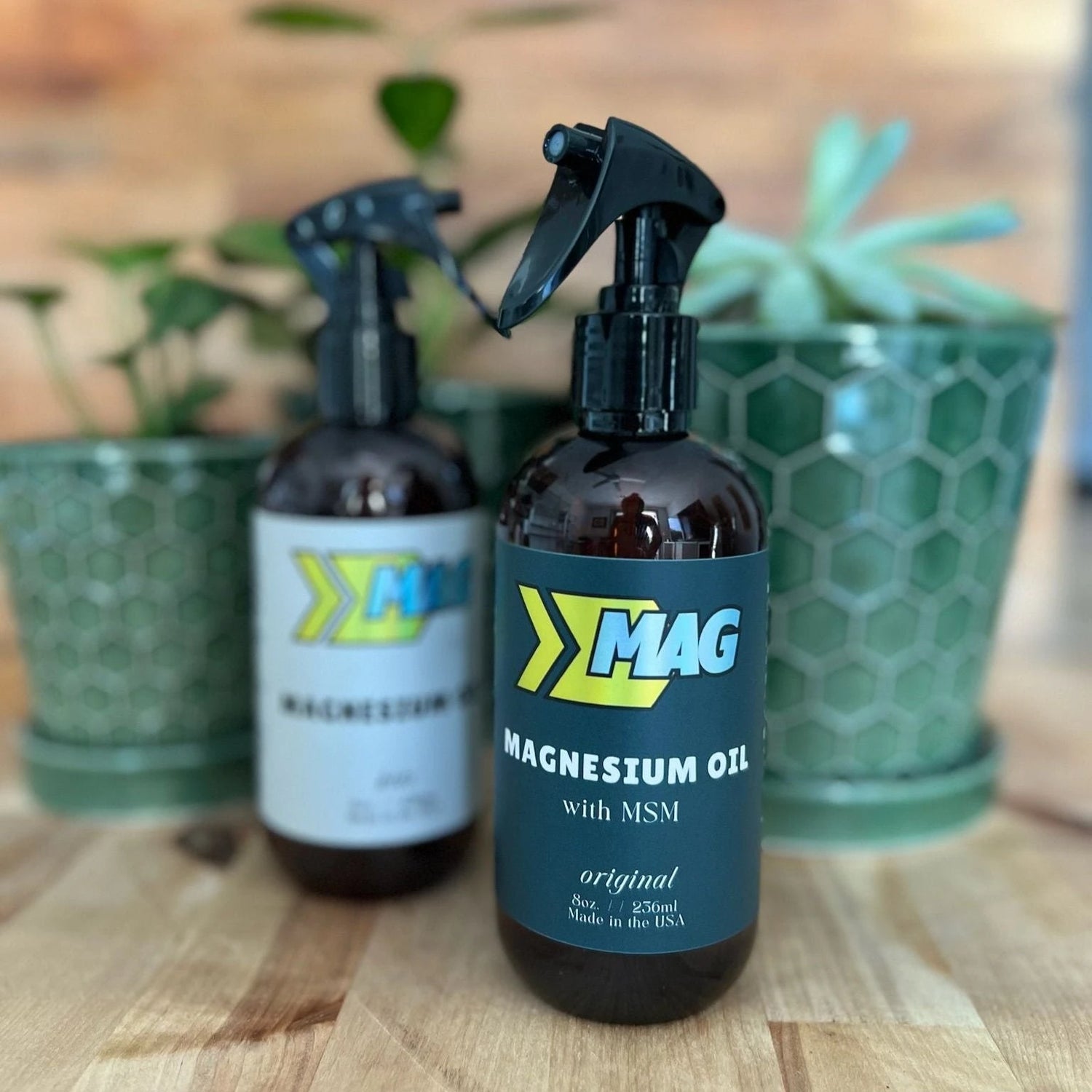 Set of MAG Recovery Magnesium Oil with MSM bottles in various sizes, featuring amber bottles with black spray tops and green, yellow, light blue MAG logo, displayed on a wooden surface